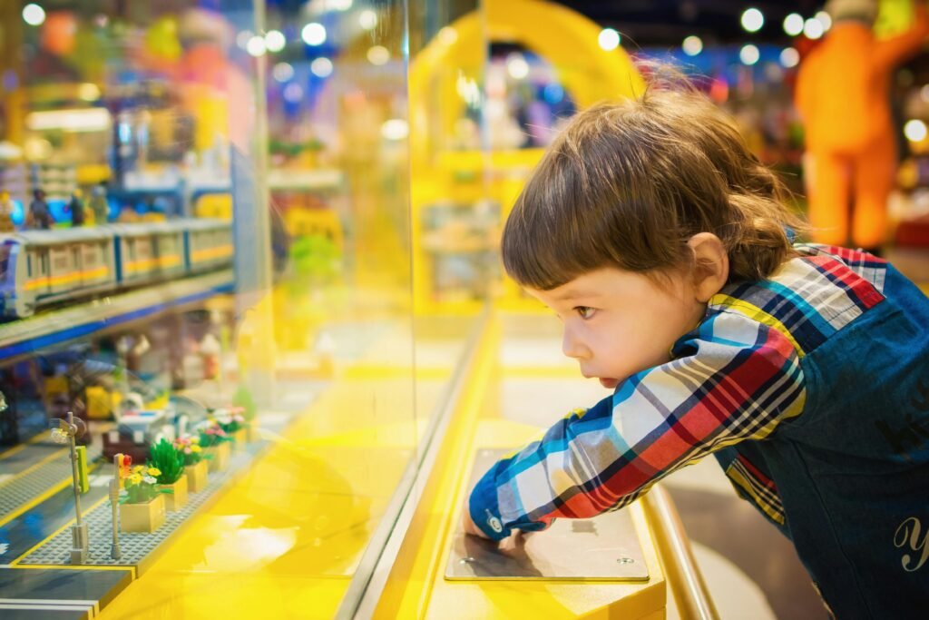 pexels-photo-1620675-1620675 A young boy intently observes a colorful toy train display in a vibrant toy store.